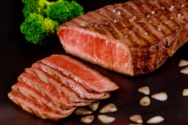 istock Juicy cooked beef sirloin with broccoli on black background. 1215725783