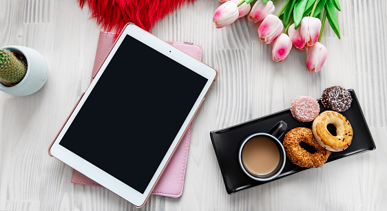 Tablet on a nice decorated white wooden table background. Styled design photography. Textures and mockup concept