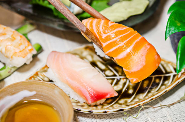 istock Salmon sashimi in chopsticks on sashimi set table 1215726677