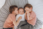 Brothers playing with baby on the bed