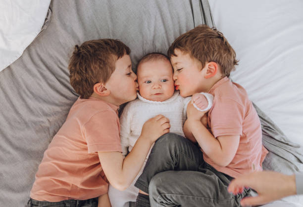 istock Brothers playing with baby on the bed 1215727008