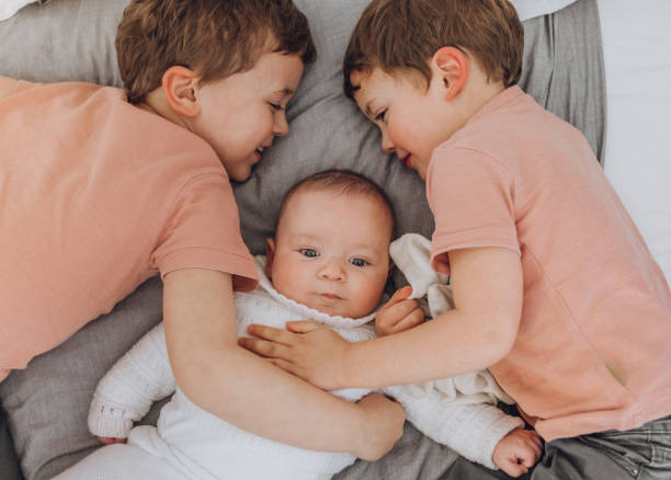 istock Brothers playing with baby on the bed 1215727742