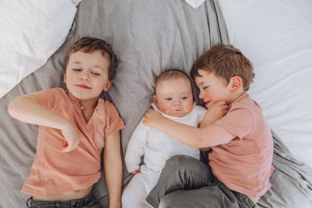 istock Brothers playing with baby on the bed 1215727811