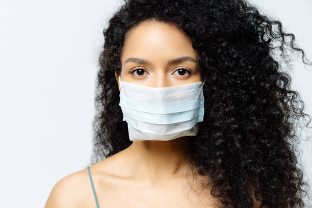 serious afro american woman tries to stop virus and epidemic disease, stays at home during infectious outbreak, wears medical mask, isolated on white background, being hospitalized, diagnosed - russian influenza epidemic virus flu virus imagens e fotografias de stock