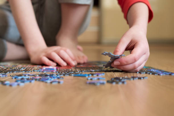 istock Boy collect puzzle sitting on the floor. Solving difficult tasks or stay at home concept. Soft focus. Zero angle 1215731942