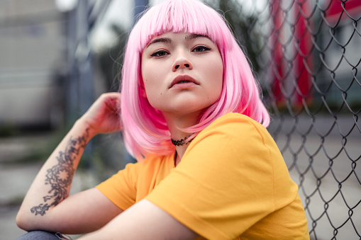 Bonita joven mujer asiática con el pelo rosa y tatuaje photo