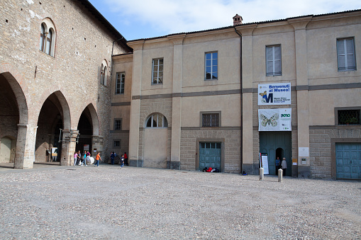 Square Piazza della Cittadella and Civic Museum of Natural Sciences in Bergamo. At facade is a banner for exhibition. A few people are outside of buildings.