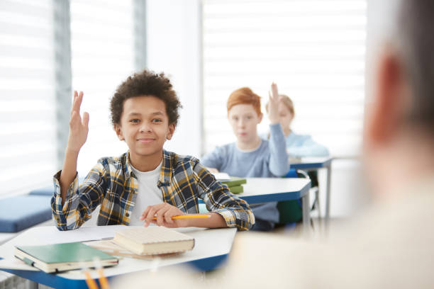 istock Smiling African Boy Raising Hand in School 1215734465