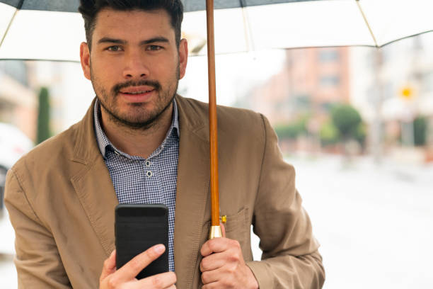 istock Young man waits for his Uber in the street while it rains 1215736162