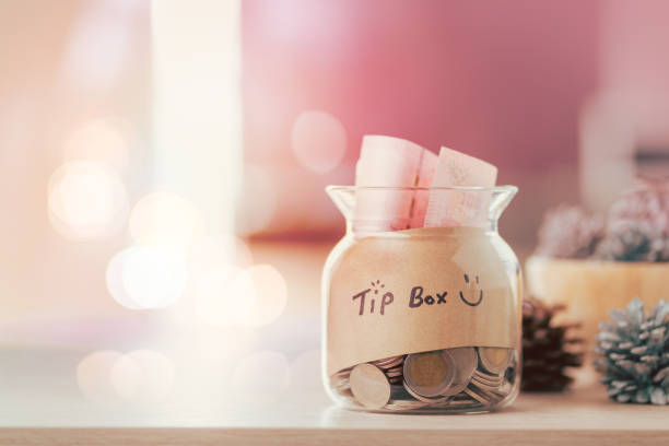 istock Glass jar with tip box tag and money coins inside 1215736697