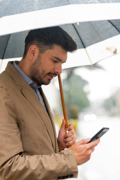 istock Young man waits for his Uber in the street while it rains 1215737781