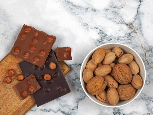 istock Broken chocolate bars and raw nuts on gray marble background 1215739245