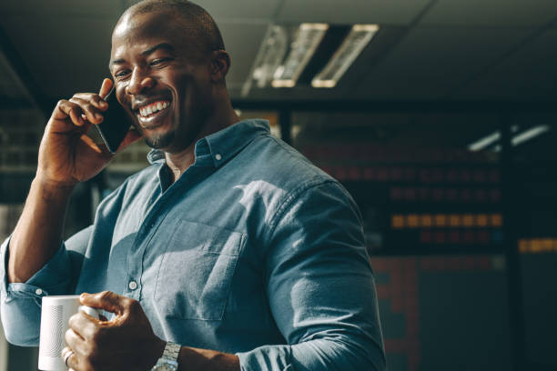 Smiling businessman with coffee talking on cellphone