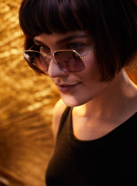 istock Stylish young woman standing against a gold background 1215739295