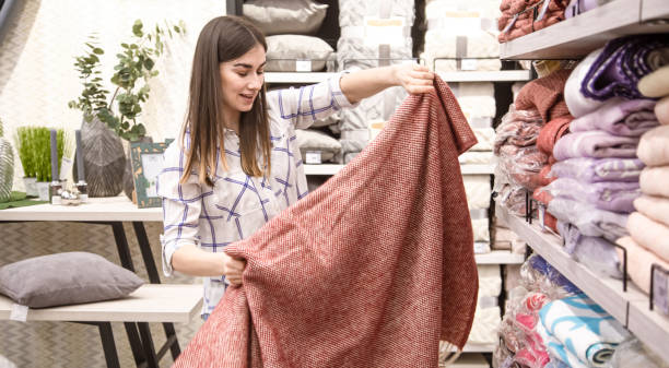 a young woman in a store chooses textiles. - bedding merchandise market textile imagens e fotografias de stock