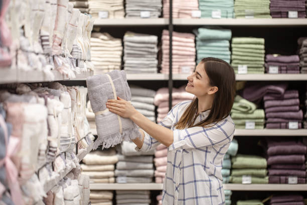 a young woman in a store chooses textiles. - bedding merchandise market textile imagens e fotografias de stock