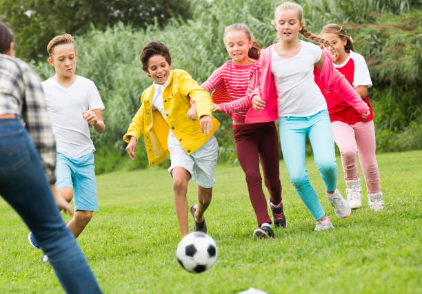 istock Cheerful children are jogning with ball 1215746783