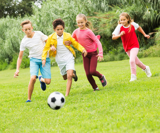istock Kids playing football in park 1215746785