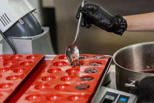 istock Confectioner in gloves makes chocolates in forms 1215750462