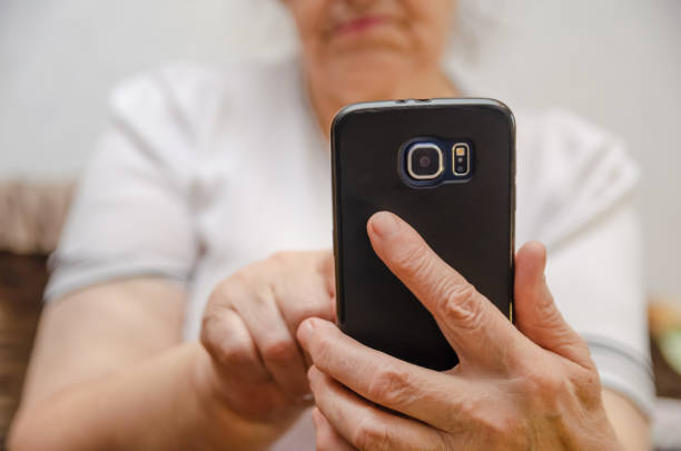 черный мобильный телефон в руке пожилой женщины крупным планом - senior women caucasian one person religion стоковые фото и изображения