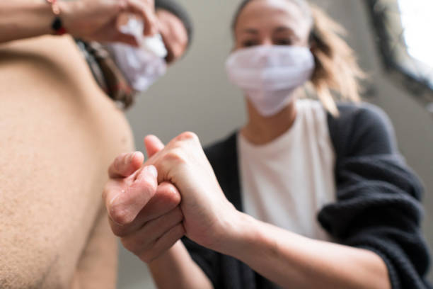 istock Two people wearing a mask using antibacterial gel to prevent covid 19 1215754496