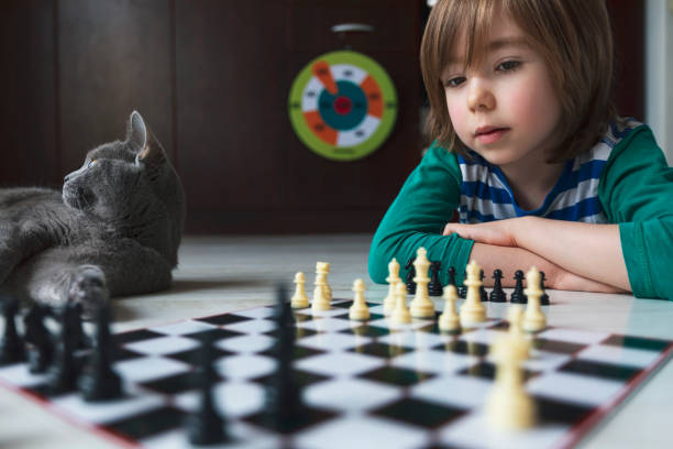 istock Little boy playing chess. Cat next to him. 1215754592