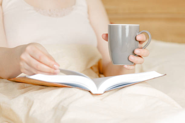 istock woman lying down on bed reading a book at home, self-isolation 1215758641