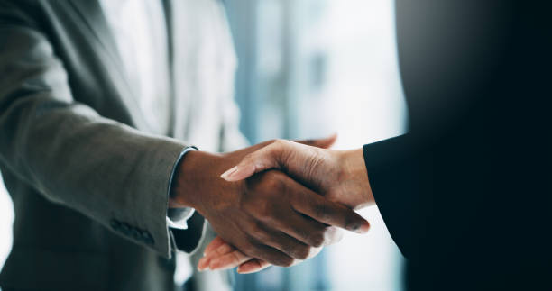 This merger will see the potential growth of our business Closeup shot of two unrecognisable businesspeople shaking hands in an office business stock pictures, royalty-free photos & images
