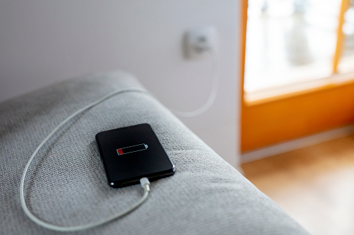 Smart phone with USB cable on sofa charging,plugged into electrical outlet
