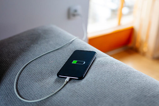 Smart phone with USB cable on sofa charging,plugged into electrical outlet