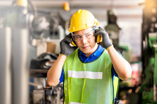 Professional technicians wear protective equipment and hard hats in large industrial plants. Protective and Safety Equipment eye wear, ear plug, vis clothes and protective helmet. stock photo