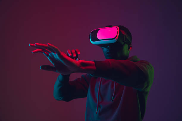 istock African-american man's portrait in VR-headset isolated on gradient studio background in neon light 1215761099