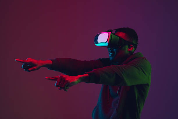 istock African-american man's portrait in VR-headset isolated on gradient studio background in neon light 1215761114