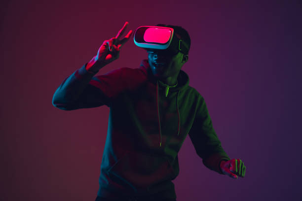 istock African-american man's portrait in VR-headset isolated on gradient studio background in neon light 1215761133