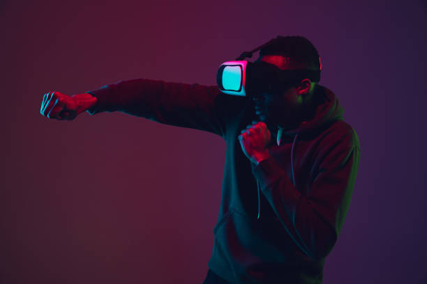 istock African-american man's portrait in VR-headset isolated on gradient studio background in neon light 1215761137