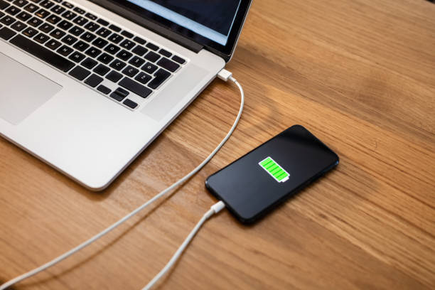 istock Smart phone charging with USB cable at laptop 1215762941