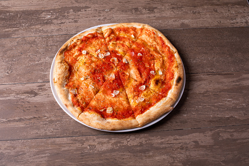 details of tomato garlic pizza on a wooden background
