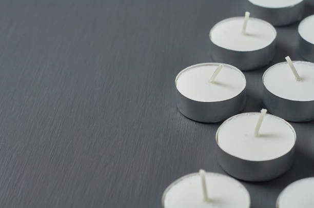 Many circle candles in metal holder on dark concrete surface