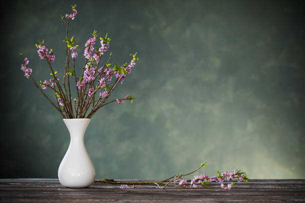 istock spring flowers in vase on old wooden table on background green wall 1215765517