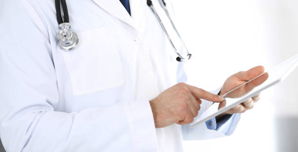 istock Doctor man using tablet computer for network research or virtual disease treatment, hands close-up. Perfect medical service in clinic. Modern medicine, medic data and healthcare concepts. Toned picture 1215766617