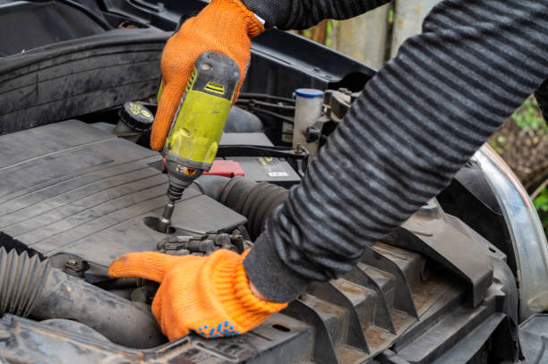 istock Male auto mechanic unscrews a nut on a car engine with a screwdriver 1215766726