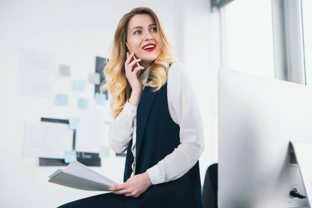 istock young woman manager holding documents in her hands, looks busy while having phone conversation with business partner, multitasking, work concept 1215766826