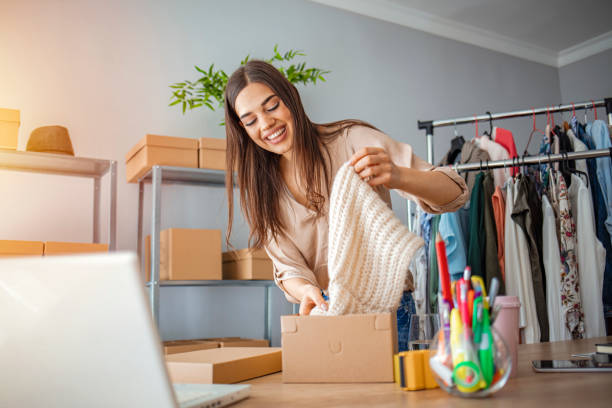 Young woman selling products online and packaging goods for shipping Young woman selling products online and packaging goods for shipping. Women, owener of small business packing product in boxes, preparing it for delivery market vendor stock pictures, royalty-free photos & images