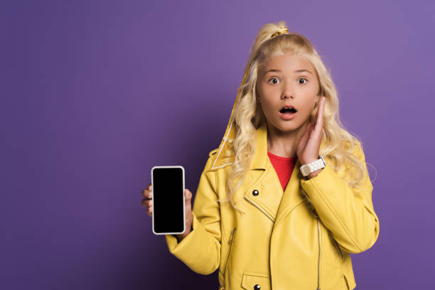 istock shocked kid holding smartphone with copy space on purple background 1215772012