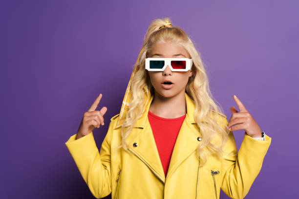istock shocked kid with 3d glasses pointing with fingers on purple background 1215772040