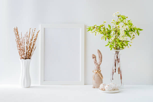 istock Home interior with easter decor. Mockup with a white frame and spring flowers in a vases on a light background 1215773275