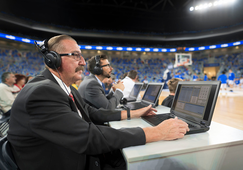 Basketball commentators wearing headphones using laptops in Arena Stozice, Ljubljana, Slovenia.