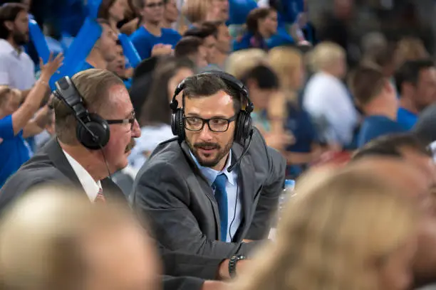 Basketball commentators wearing headphones talking with each other while watching match in Arena Stozice, Ljubljana, Slovenia.