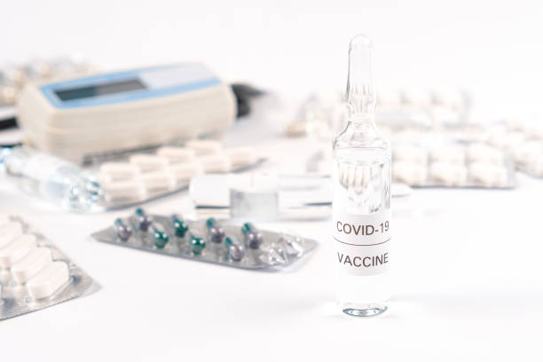 Ampoule with COVID-19 medicine on a white table with medical equipment and capsules in packs Coronavirus vaccine. Ampoule with COVID-19 medicine on a white table with medical equipment and capsules in packs. Close-up. Development and use of a cure for a new virus crista ampullaris photos stock pictures, royalty-free photos & images