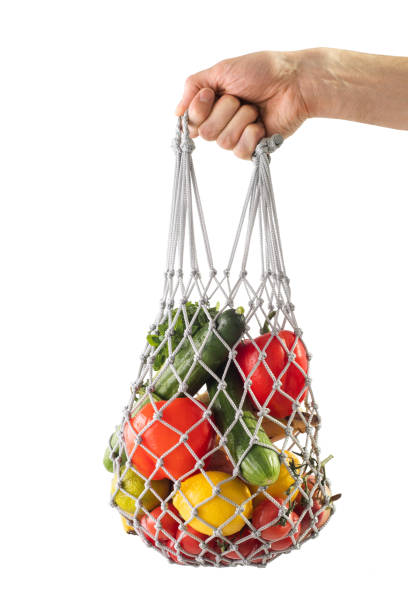istock Shopping bag mesh with healthy vegetables on a white isolated background. Zero waste. Man's hand holding bag with mesh products. 1215779579